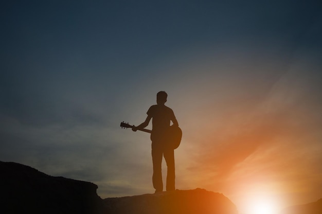 Uma silhueta de um homem segurando uma guitarra de mãos dadas