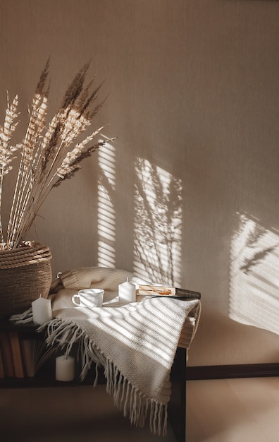 Uma sombra de cortinas na parede branca e mesa de madeira pela manhã. Uma xícara de café e um livro