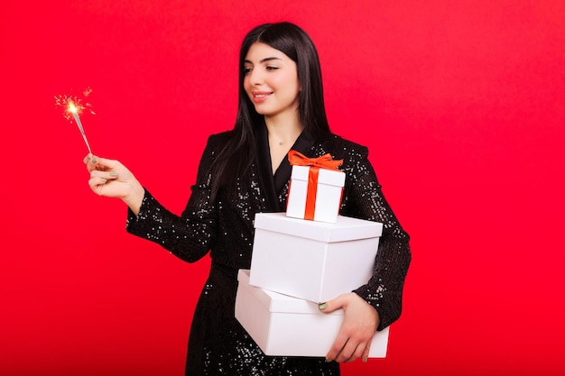 Uma surpresa para os entes queridos Uma jovem segura caixas contendo presentes de Natal Estúdio filmando em um fundo vermelho