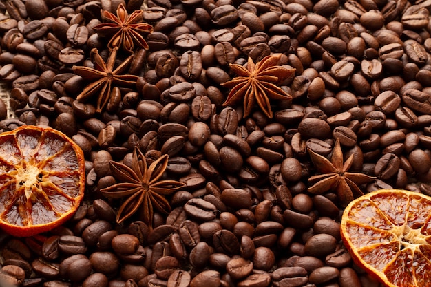Uma tabela coberta com os feijões de café com estrelas do anis e as laranjas secadas. plano de fundo para um menu de café.