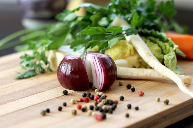 Uma tábua de corte com cebola roxa e outros ingredientes, incluindo pimenta-do-reino, alho e outros temperos.