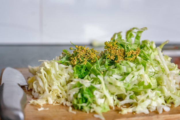 uma tábua de corte com um monte de vegetais verdes como cenoura de repolho