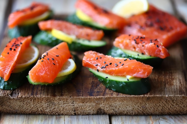 Uma tábua de corte de madeira com fatias de salmão e pepino.