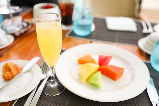 Uma taça de champanhe e uma taça de champanhe em uma mesa com um prato de frutas e uma taça de champanhe.