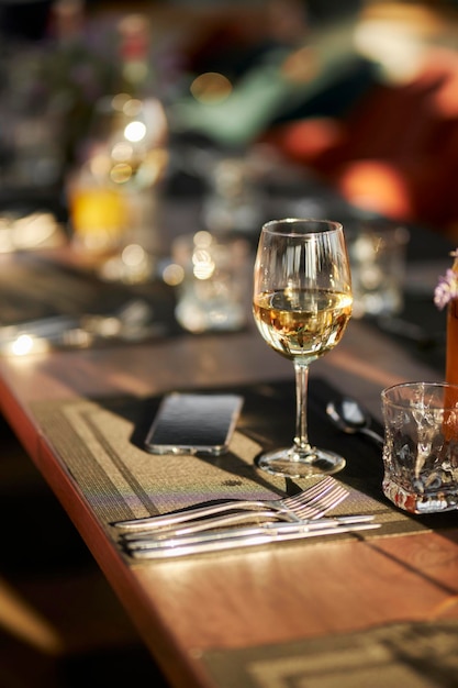 Foto uma taça de vinho branco está sobre a mesa uma taça de vinho e um telefone celular sobre a mesa de um restaurante