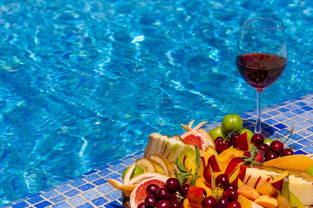 Uma taça de vinho com fatias de frutas à beira da piscina