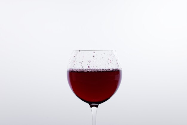 Foto uma taça de vinho tinto em frente a uma parede branca