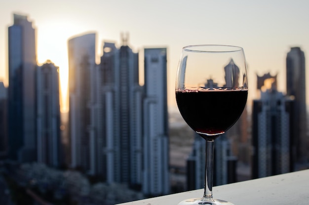 Uma taça de vinho tinto no fundo da cidade ao pôr do sol