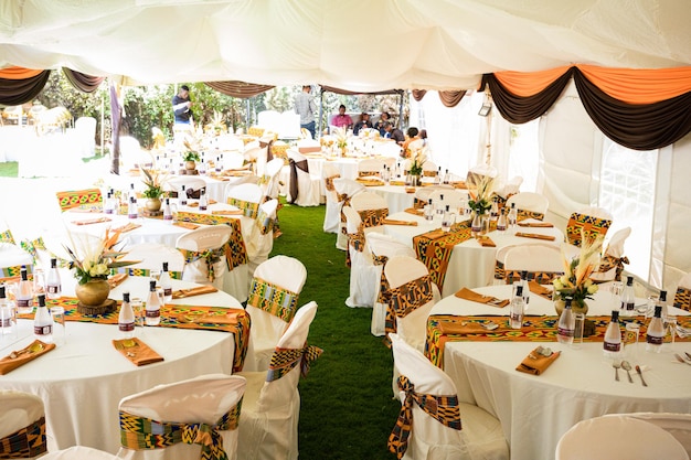 uma tenda com mesas e cadeiras preparadas para uma recepção de casamento