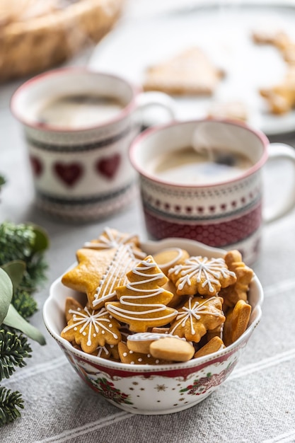 Uma tigela cheia de pão de natal na mesa levou uma coroa do advento e duas xícaras com ponche de café ou chá