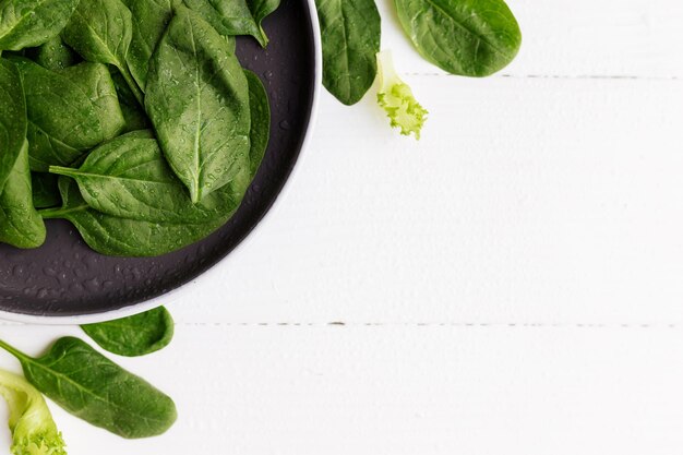 Foto uma tigela com salada verde fresca, folhas de espinafre, alface, manjericão sobre um fundo branco, alimentação saudável.