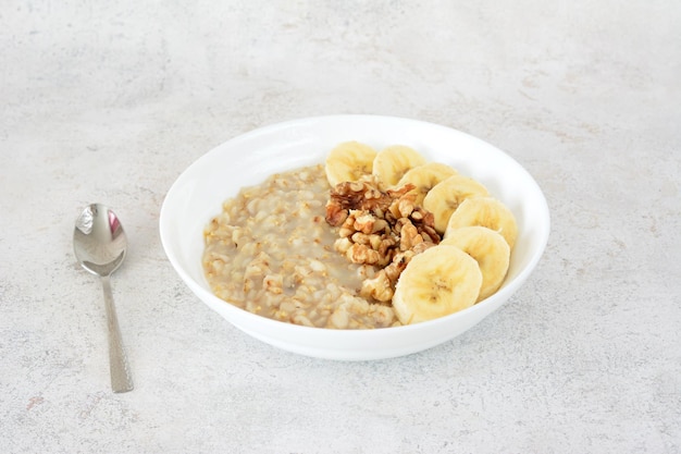 uma tigela de aveia com bananas e uma colher ao lado dela