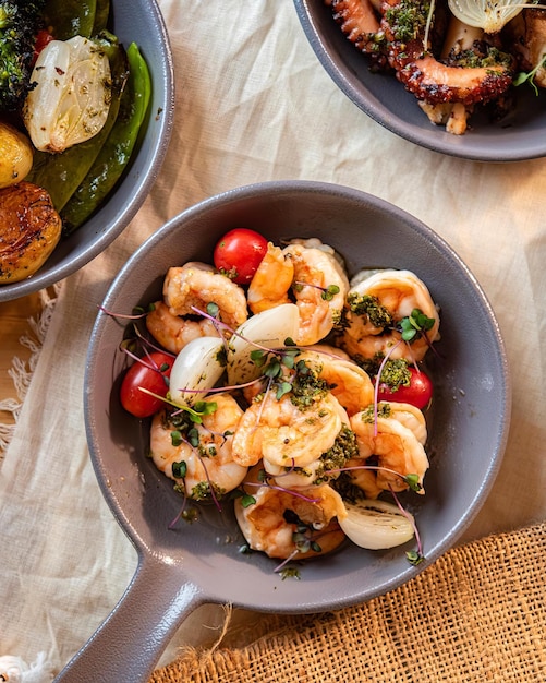 Uma tigela de camarão com legumes e carne em uma mesa.