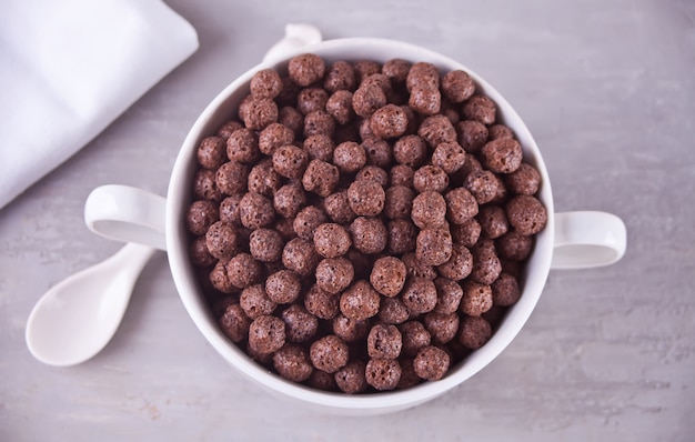 Uma tigela de cereal de bolas de chocolate seco na mesa cinza para café da manhã de saúde