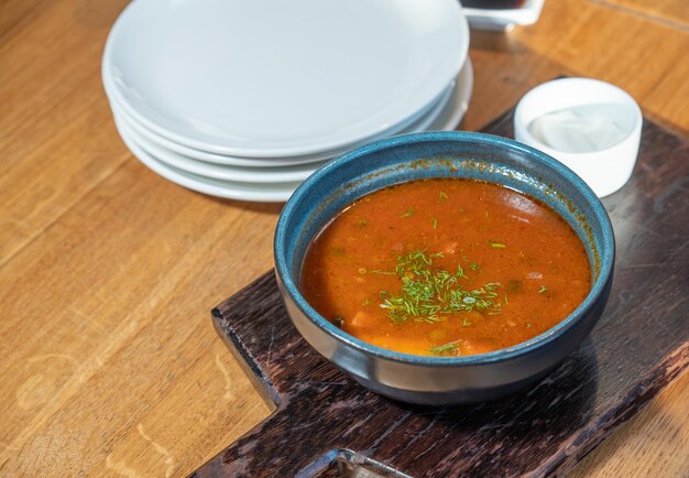 Uma tigela de comida com uma colher e uma pilha de pratos ao lado.