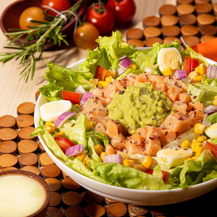 Foto uma tigela de comida com uma salada e alguns tomates na mesa