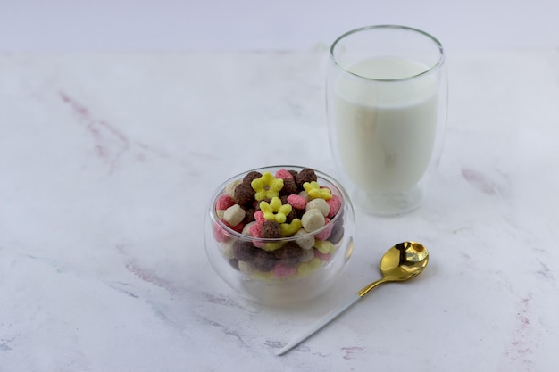 Uma tigela de lanches em forma de corações de bola e flores em uma mesa de mármore branca Cereal de café da manhã e um copo de leite