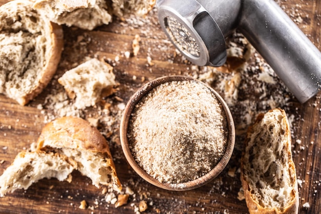 Uma tigela de madeira cheia de migalhas de pão e pão seco velho ao redor