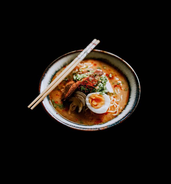 Foto uma tigela de ramen com pauzinhos e ovos.