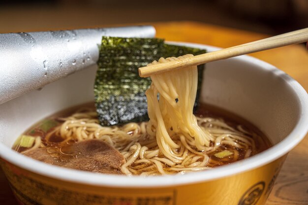 Uma tigela de ramen com uma colher e um par de pauzinhos.