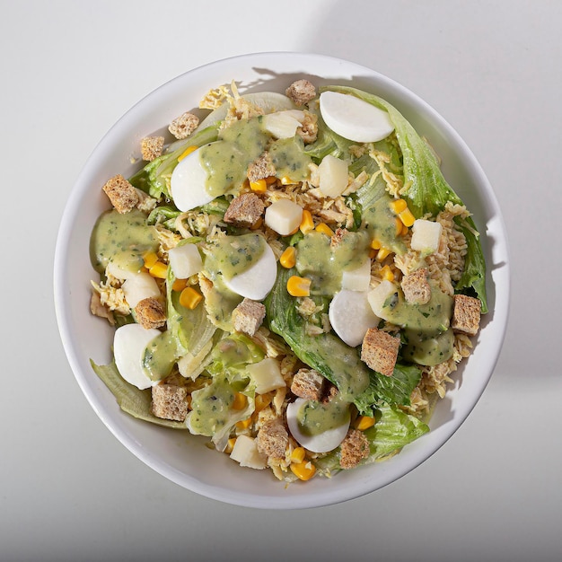 Foto uma tigela de salada com molho verde por cima.