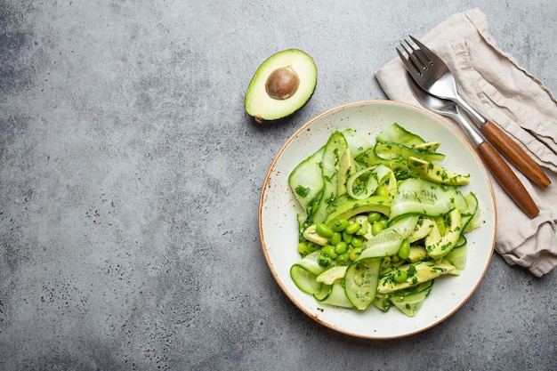 Uma tigela de salada de abacate verde vegana saudável com pepinos fatiados