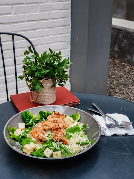 Foto uma tigela de salada de camarão sobre uma mesa com uma planta ao fundo.
