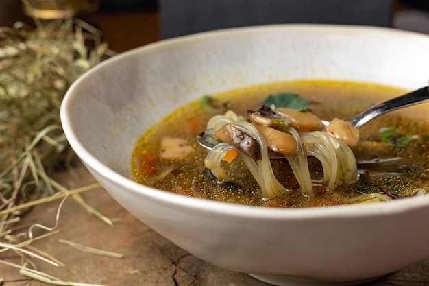 Uma tigela de sopa com cogumelos e folhas verdes sobre uma mesa.