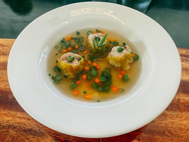 Uma tigela de sopa com um vegetal verde sobre ele