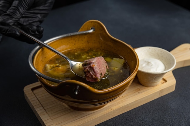 Uma tigela de sopa com uma colher de carne.