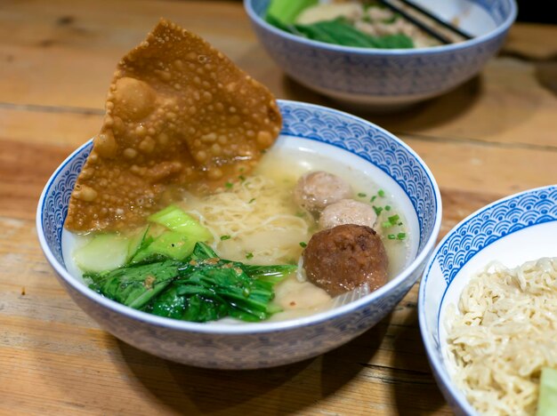 Uma tigela de sopa de bolas de carne com vegetais frescos na velha mesa de madeira