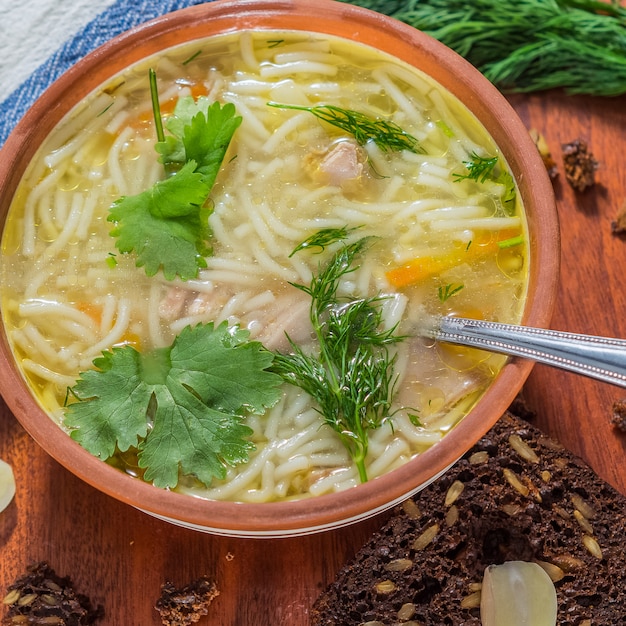 Foto uma tigela de sopa de frango caseiro e pão de grãos