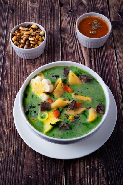 Foto uma tigela de sopa de menestron peruana com pedaços de carne macarrão picado cenouras milho e coentro para dar-lhe a cor verde