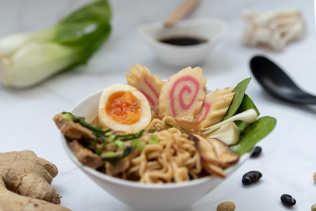 Foto uma tigela de sopa de ramen com todos os ingredientes sobre uma mesa de mármore