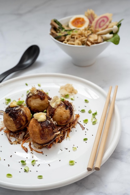 Uma tigela de sopa de Ramen e um prato de lanche Takoyaki