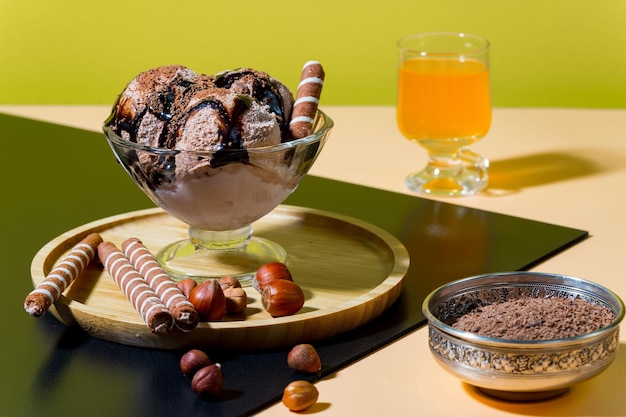 Uma tigela de sorvete com um copo de suco de laranja e um copo de sorvete com avelãs.