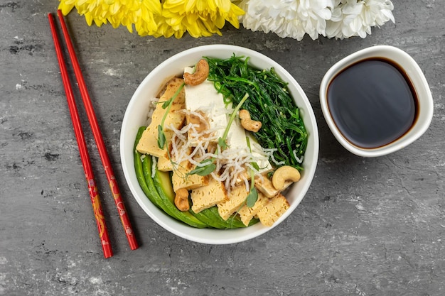 Uma tigela de tofu com uma xícara de molho de soja ao lado