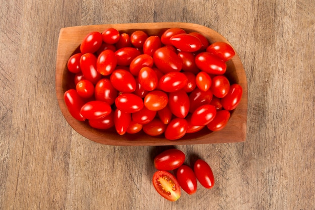 Uma tigela de tomates-uva sobre uma mesa de madeira. frutas frescas.