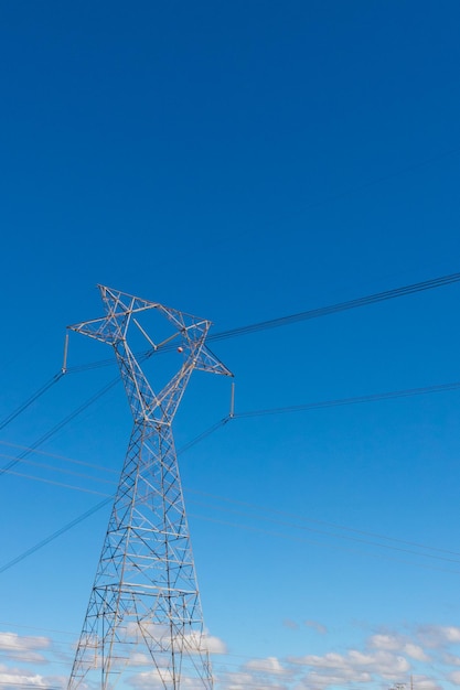 Uma torre de alta tensão de transmissão de energia na zona rural isolada no pôr do sol com algumas nuvens quentes no céu. Fotografia urbana de verão.