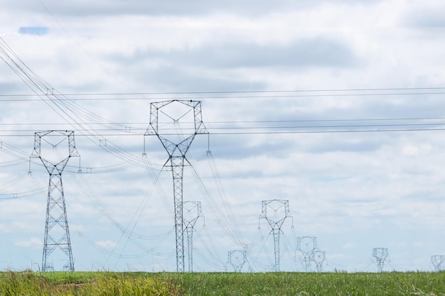 Uma torre de alta tensão de transmissão de energia na zona rural isolada no pôr do sol com algumas nuvens quentes no céu. fotografia urbana de verão.