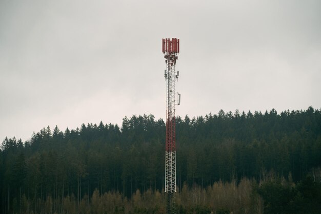 Uma torre de celular em um campo com árvores ao fundo