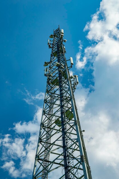 Uma torre para antenas de comunicação móvel contra um céu azul com nuvens brancas