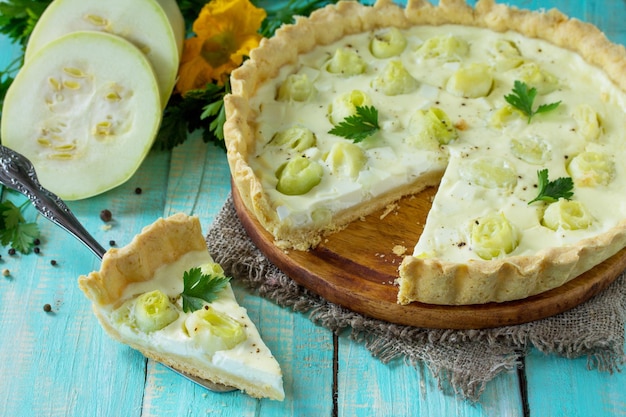 Uma torta clássica de quiche Lorraine com queijo feta com ovo de abobrinha e queijo em uma mesa de madeira de cozinha