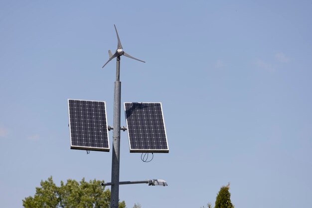 Uma turbina eólica solar é montada em um poste em frente a um céu azul.