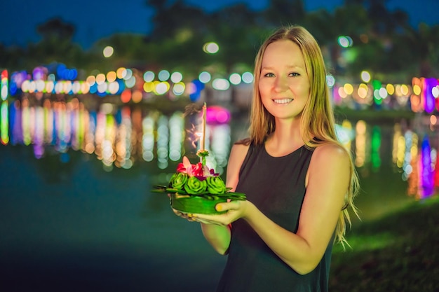 Uma turista feminina segura o loy krathong nas mãos e está prestes a lançá-lo no loy de água