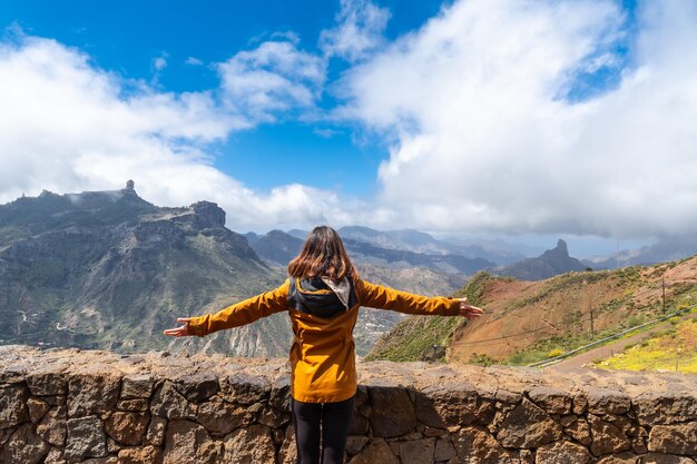 Foto uma turista olhando para roque nublo de um ponto de vista na montanha gran canaria, espanha