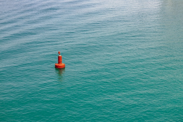 Uma única bóia vermelha em mar límpido