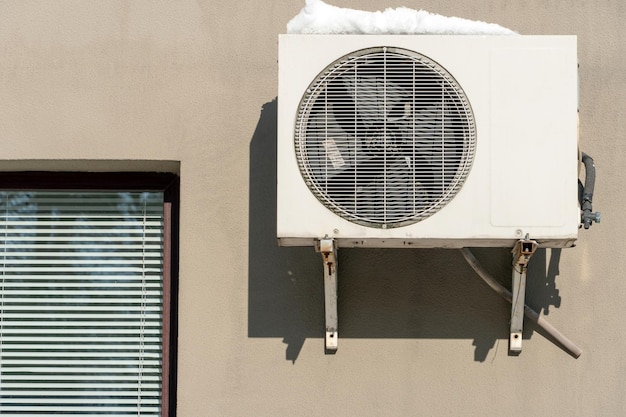 Uma unidade de ar condicionado exterior instalada na parede de um edifício residencial junto à janela instalação de reparação e manutenção de sistemas de ar condicionado em instalações residenciais