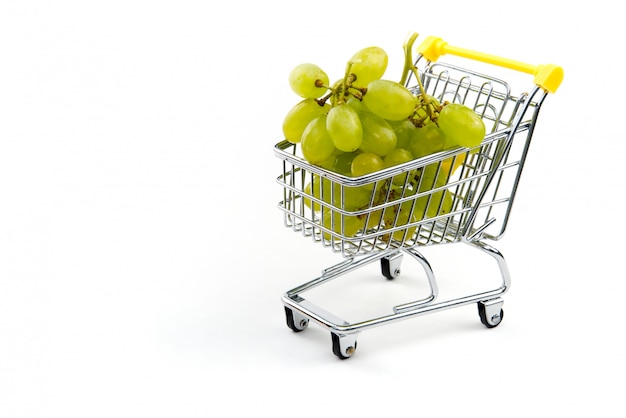 Uma uva no carrinho de compras isolado no fundo branco. Uvas verdes saborosas maduras no carrinho de compras. Conceito de negociação de uva. Conceito de compras on-line. Carrinho e uva sobre um fundo branco.