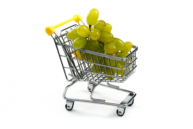 Uma uva no carrinho de compras isolado no fundo branco. Uvas verdes saborosas maduras no carrinho de compras. Conceito de negociação de uva. Conceito de compras on-line. Carrinho e uva sobre um fundo branco.